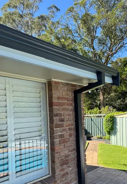 Dark fascia covers and matching guttering above a white soffit on a Central Coast brick home