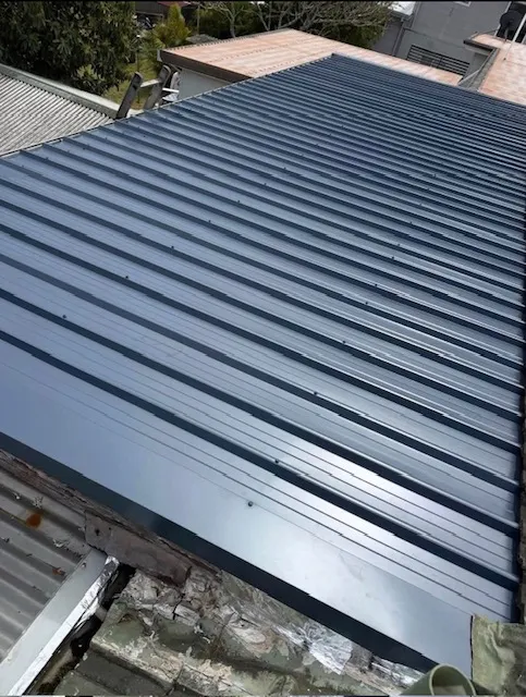 New dark metal roof sheets after roof replacement on the Central Coast